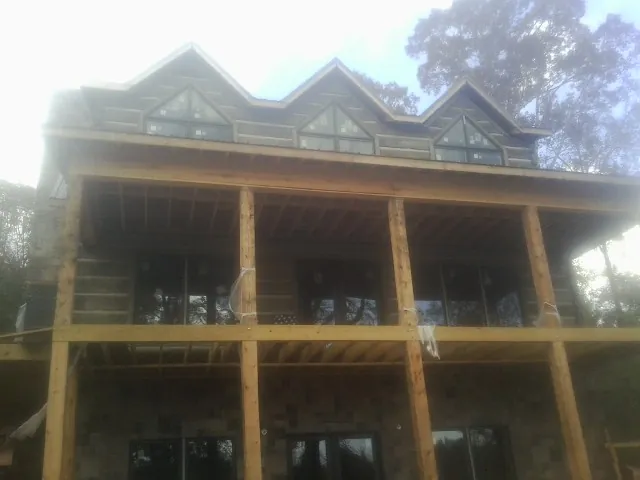 Dormers and porch framing on a large log home under construction — Roof Coating work by our crew in Rapids City