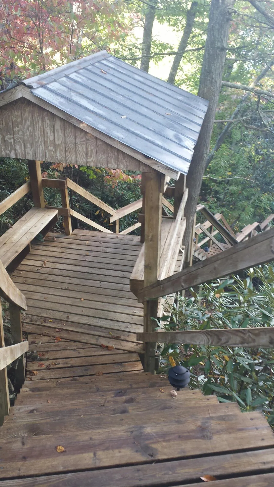 Metal roofed shelter over wooden steps on a wooded walkway — Skylight Repair & Installation work by our crew in Rapids City