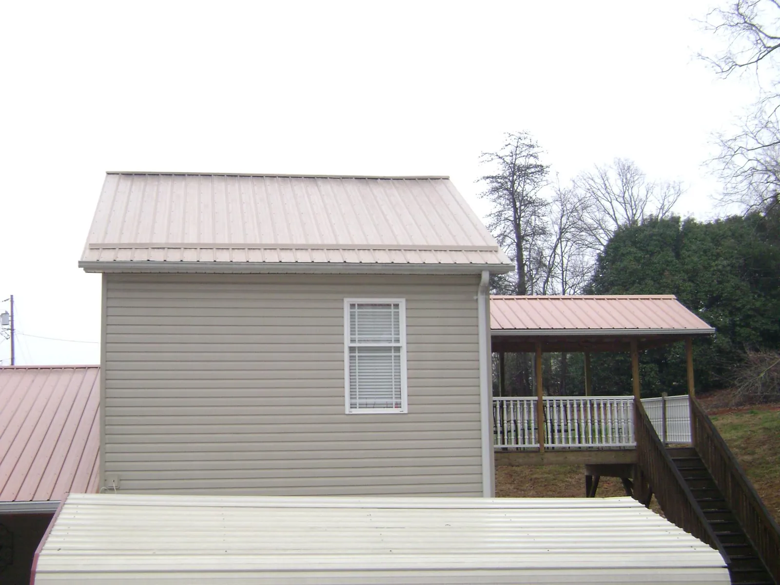Tan metal roofs on a two story addition and attached porch, from a Roof Replacement job in Rapids City